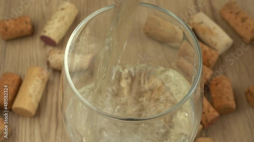 Wine is poured into a glass on the background of wine corks. photo