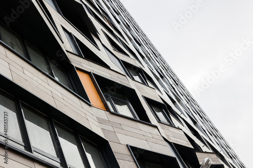 The exterior wall of a contemporary commercial style building with aluminum metal composite panels and glass windows. The futuristic building has engineered diagonal cladding frame panels.