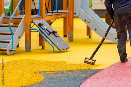 Laying a rubber coating of crumbs on a children\'s playground. Roller leveling rubber mulch.