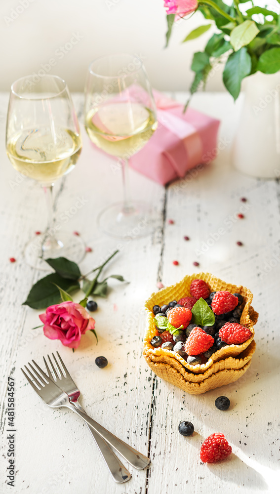 S.Valentine's Day concept. Mix of berries in a waffle basket, sparkling wine in two glasses, roses and gift S.Valentine's Day concept. Mix of berries in a waffle basket, sparkling wine in two glasses, roses and gift