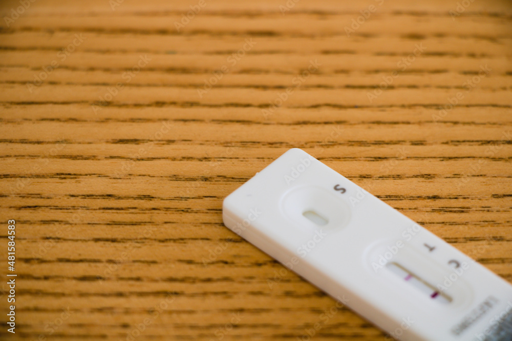 Close up of positive lateral flow test, out of focus, isolated on wooden background with copy space Close up of positive lateral flow test, out of focus, isolated on wooden background with copy space