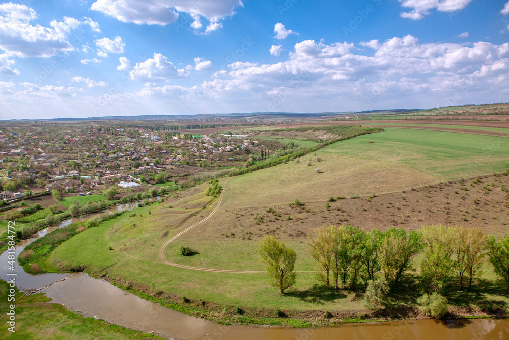 Traditional village located in Moldova . Rustic settlement situated at river bank . Spring countryside and meadows view from above