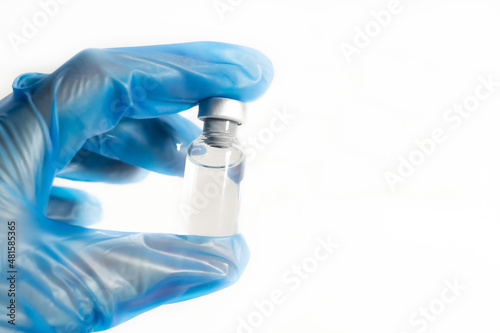 Vaccination concept. COVIC-19 cororavirus vaccine. The doctor's hands with blue gloves hold the vaccine bottle, on a white background.