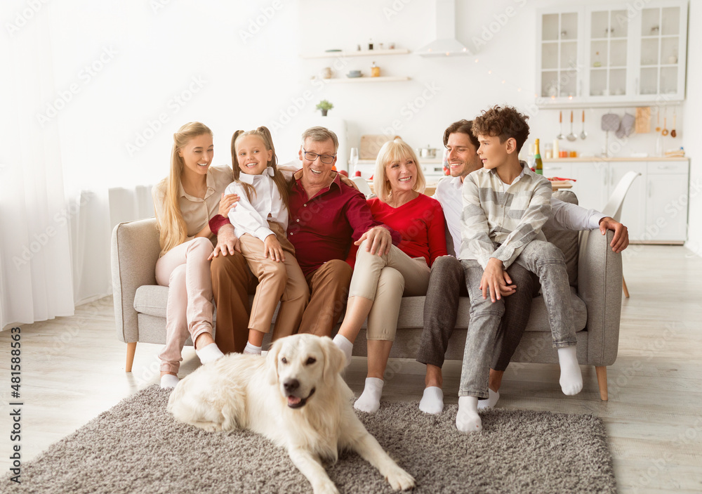 Portrait of big multi generation family with their pet dog sitting on couch, smiling at camera, having fun at home