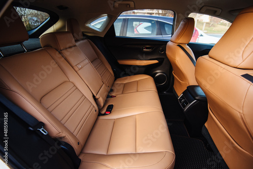Luxury car interior made of yellow leather. Leather folding armrest armrest with cup holders in rear seats inside a vehicle. Clean leather interior: yellow rear seats, headrests and belts. Film noise © Oleksandr
