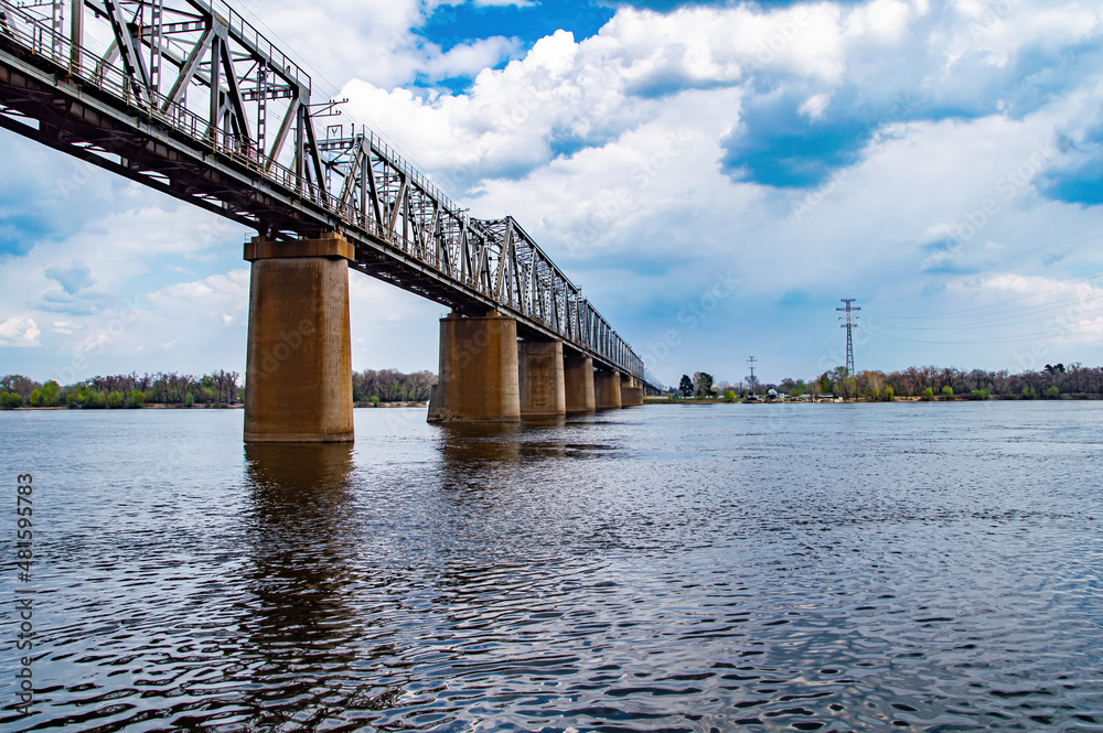 Concrete supports of the railway bridge over the river. Water crossing. Railway track. Bridge construction. Moving over water. Transport crossing. Dnepr River. Overcast sky. Industrial design.
