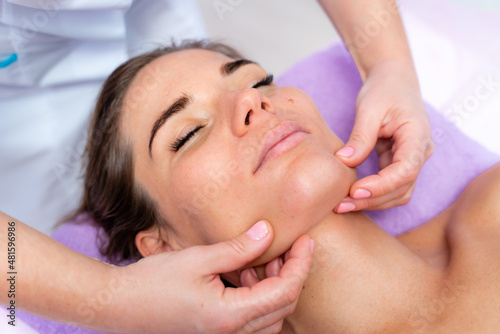 Relaxing massage. European woman getting facial massage in spa salon, side view