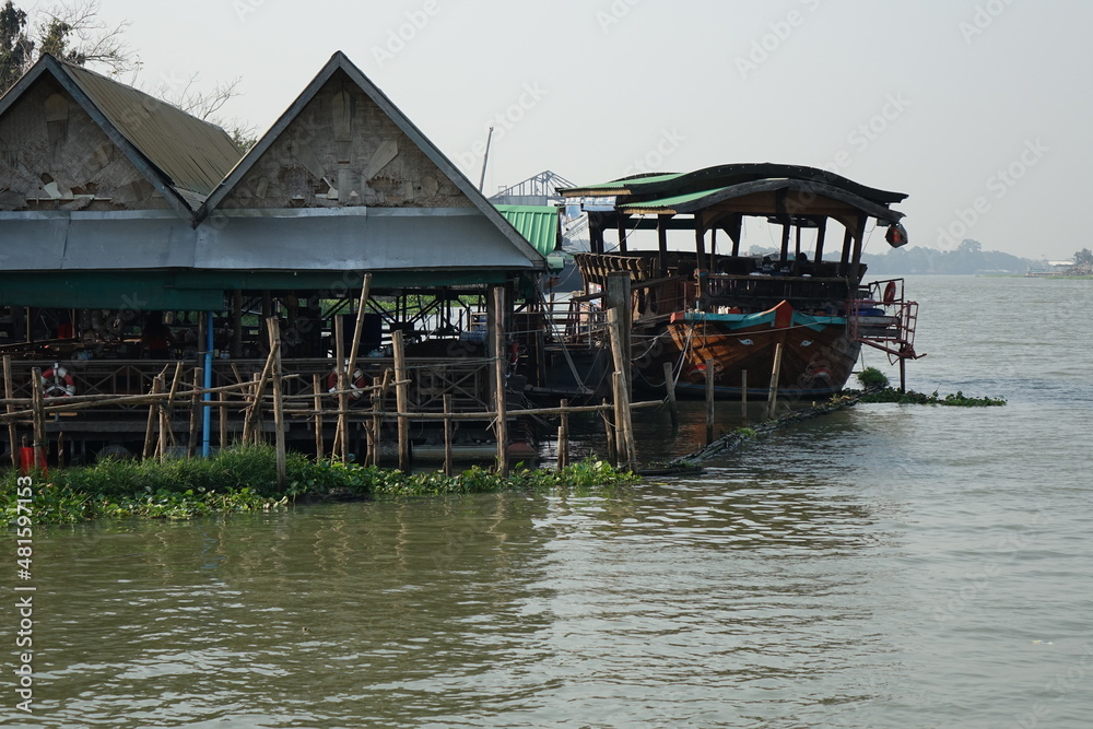 Stilt huts and boat on River Chao Phraya between Bangkok and Ayutthaya, Phatum Thani, Thailand