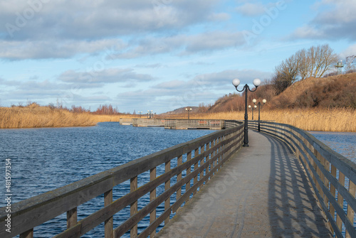 Wooden walkway through the lake. Winter lake  floating walkway and reeds in Yantarny  Kaliningrad oblast