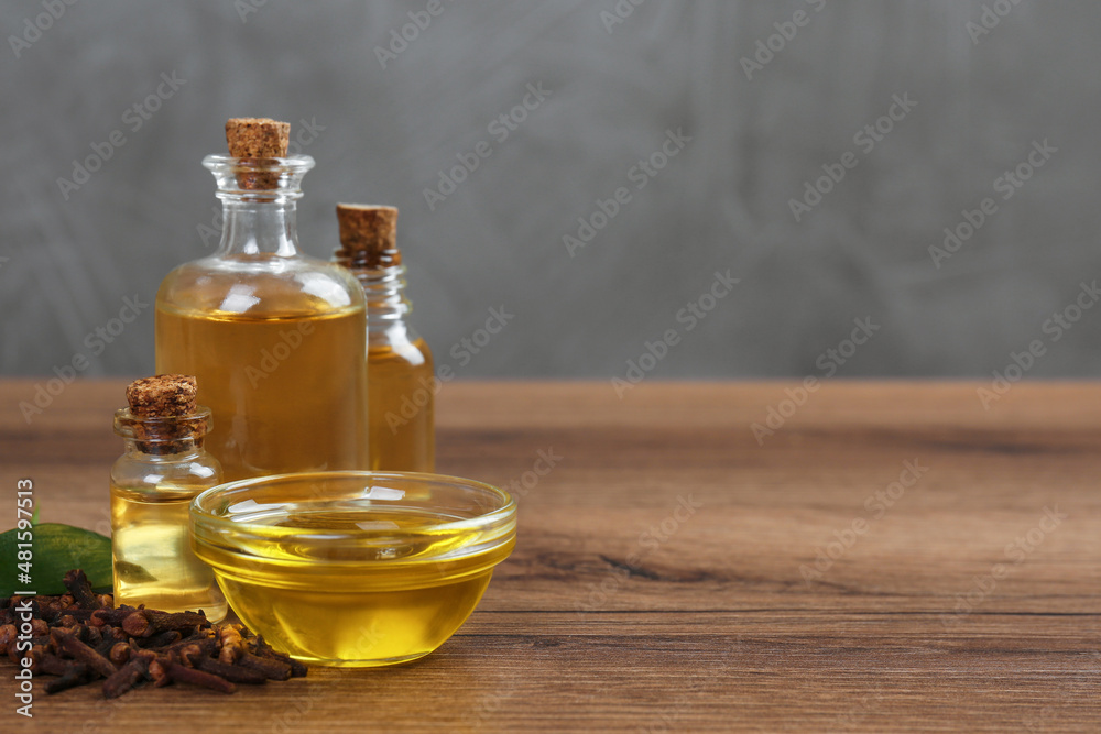 Essential oil and dried cloves on wooden table. Space for text Essential oil and dried cloves on wooden table. Space for text