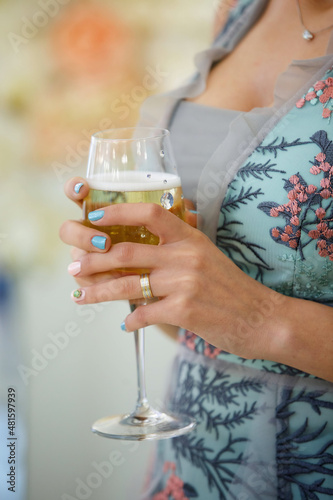 A glass of alcoholic beverage in the hands of an adult.