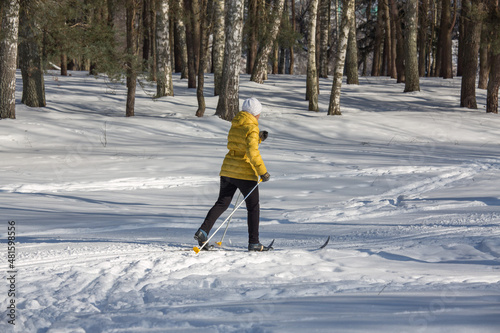 Woman skier walking by the snow in a winter park. Winter sports and leisure outdoors. Selective focus.