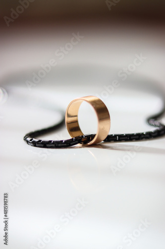 golden ring on a white background. Golden ring. ring and black chain on white background