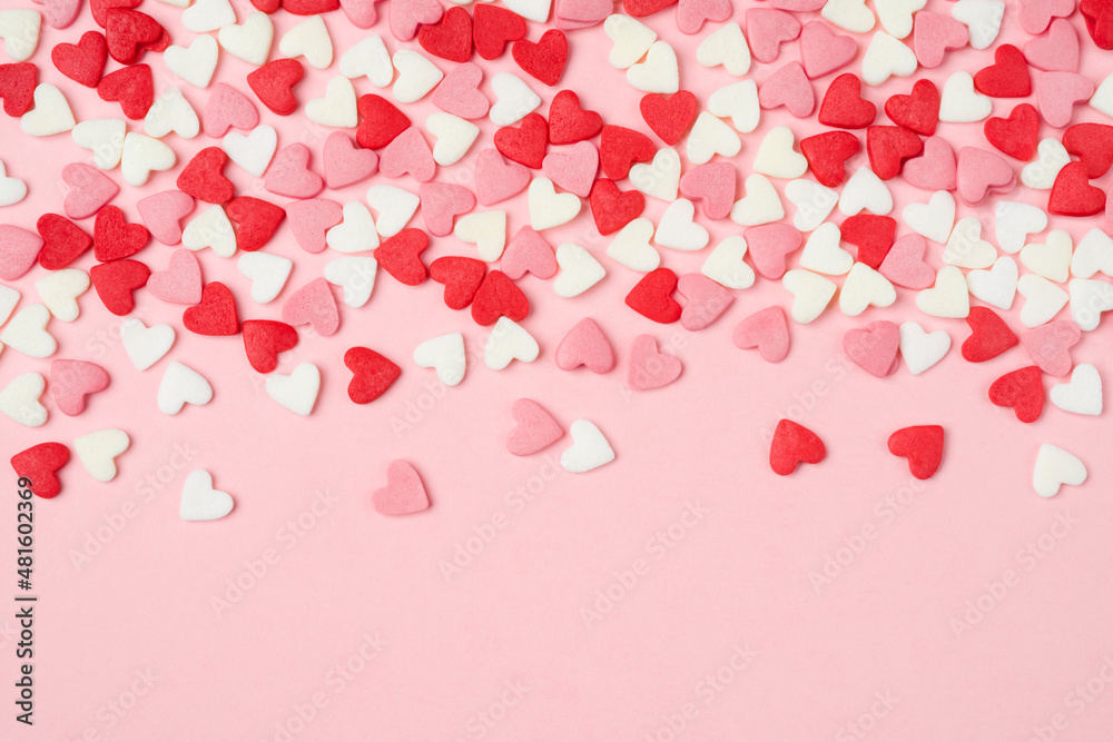 Many colorful sugar hearts on pink background with copy space