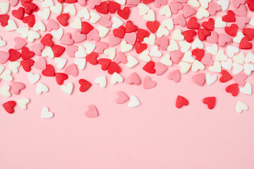 Many colorful sugar hearts on pink background with copy space