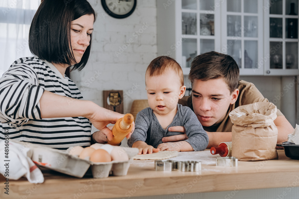 Mother and two sons cooking together in the kitchen Mother and two sons cooking together in the kitchen