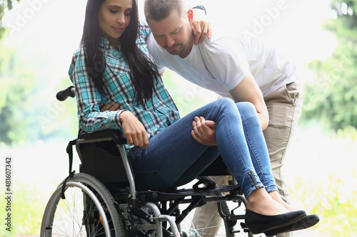 Man husband take woman in arms, disabled wife on wheelchair
