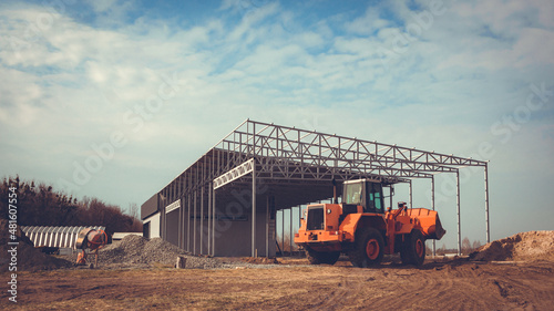 Construction of a large hangar in the countryside with the help of heavy machinery.