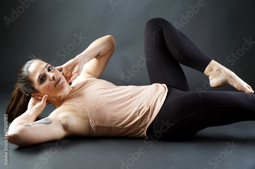 Fit woman exercising on mat doing situps and stretching exercises 