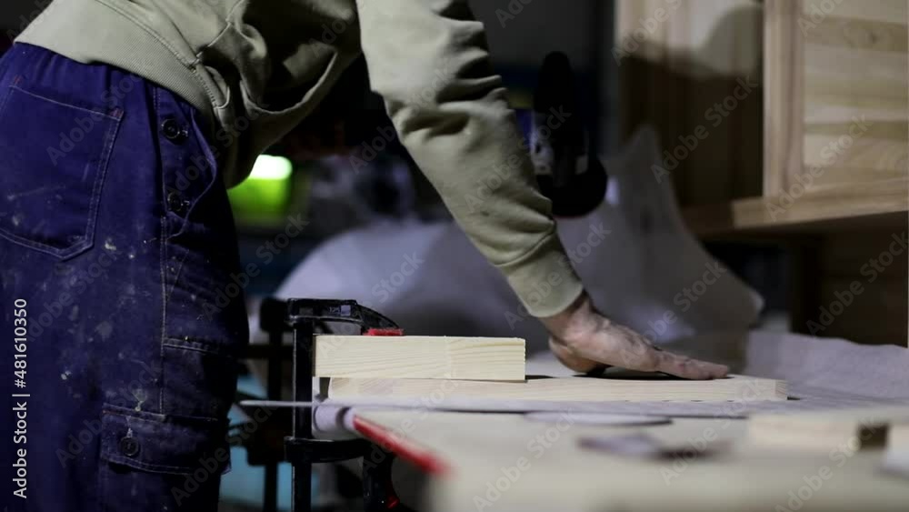 Grinding board. Woodworking. Creating pedestal. Woodworker. Man in garage. Electro tool for surface treatment of board. Grinding board. Woodworking. Creating pedestal. Woodworker. Man in garage. Electro tool for surface treatment of board.