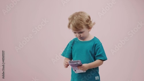 Little child boy counts money in hands and throws down on pink background. 4K footage