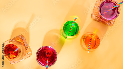 Colorful cocktails on yellow table for rainbow party with rainbow drinking straws and party accessories