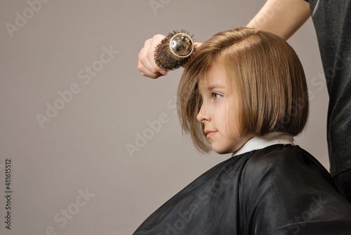 Bob Short Hairstyle. Beautiful Hair of Little Girl. Fashion Trendy Haircut. Dark Blond Child Model with Shiny Hairstyle. Hair styling Process from Hairtician. Courses in hairdressing. Beauty service.. photo