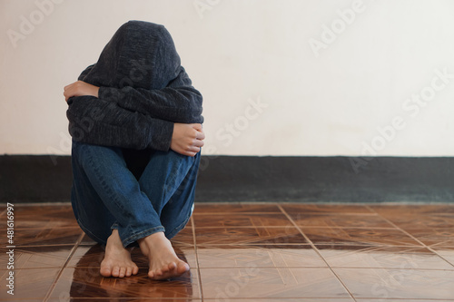 Bilde på lerret Depressed boy sits alone on the floor, feeling sad and cry, hug his knee