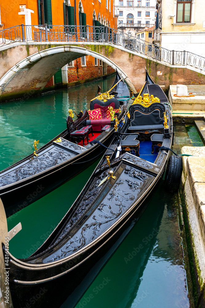 Two traditional venetian gondolas docked near the bridge in Venice, Italy