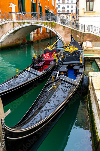 Two traditional venetian gondolas docked near the bridge in Venice, Italy #481617555