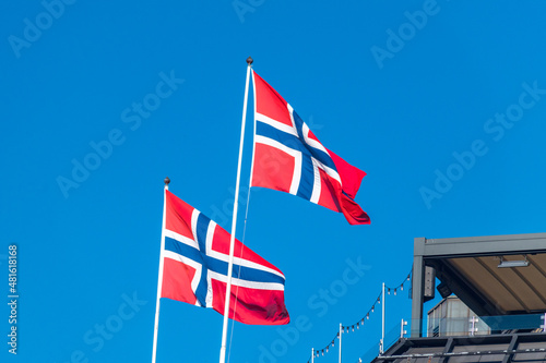 National flag and ensign of Kingdom of Norway on blue sky.