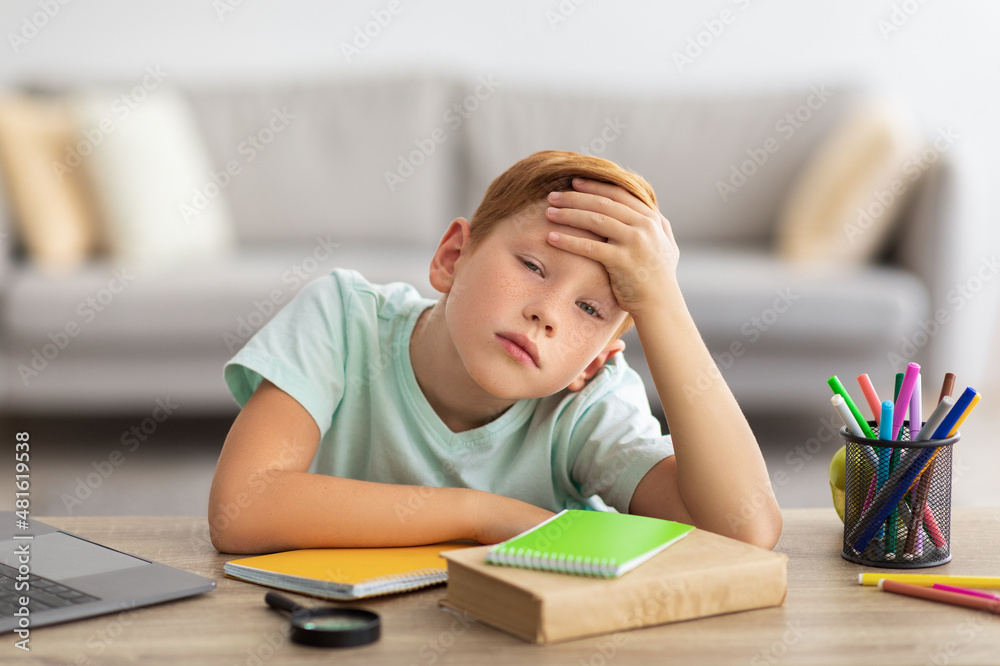 Bored boy doing homework in front of laptop at home Bored boy doing homework in front of laptop at home