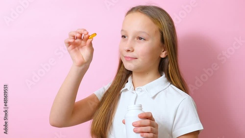 Teenage girl takes omega 3 capsules on a colored background close-up