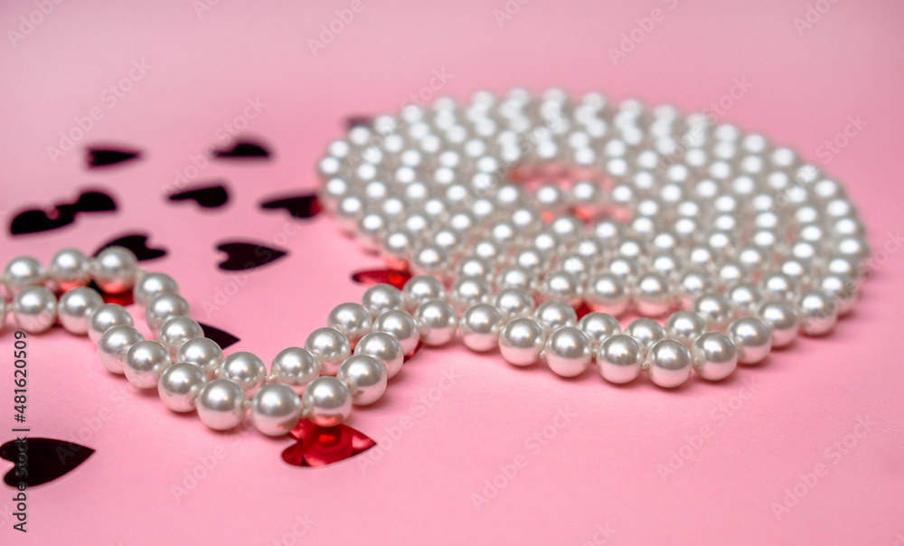 A pearl necklace lies on a pink background A pearl necklace lies on a pink background