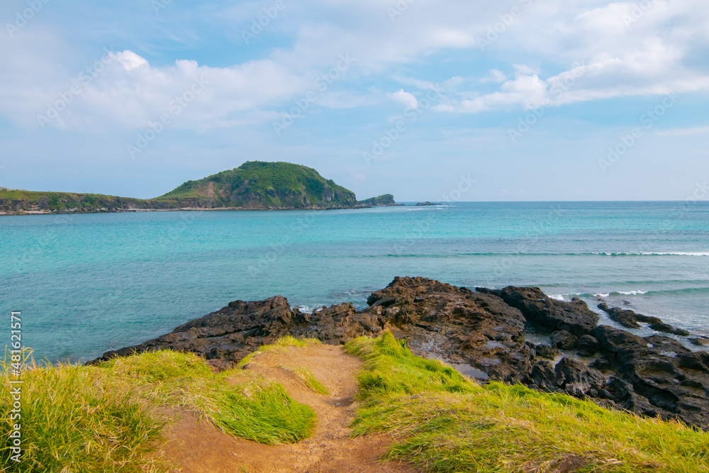 Obraz premium White sand beach and gentle waves with stunning green hills on the South side of Lombok Island, Indonesia