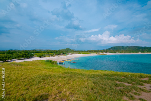 White sand beach and gentle waves with stunning green hills on the South side of Lombok Island, Indonesia