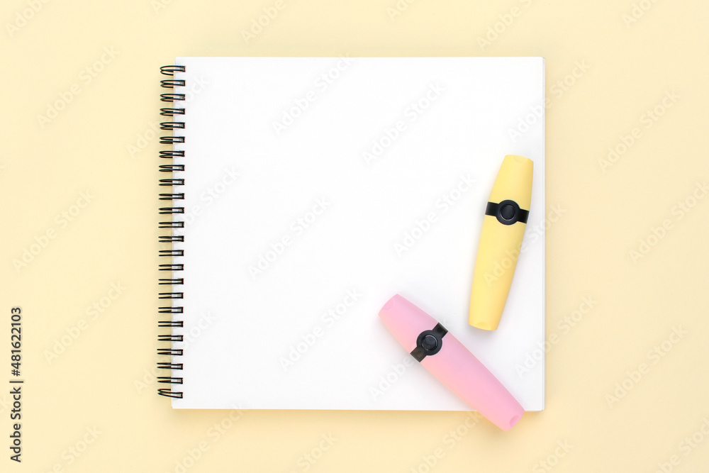 Top view sketchbook, yellow and pink marker on light wooden background Top view sketchbook, yellow and pink marker on light wooden background