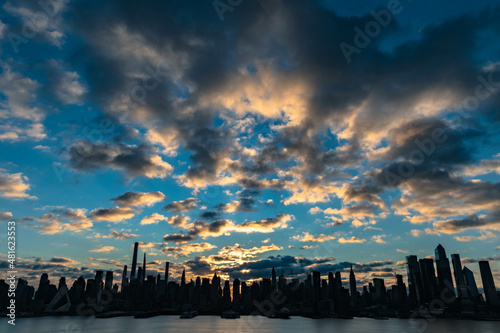 sunset over the city, Nyc skyline of Manhattan skyscrapers with stuning sky iluminated by rusing sun.