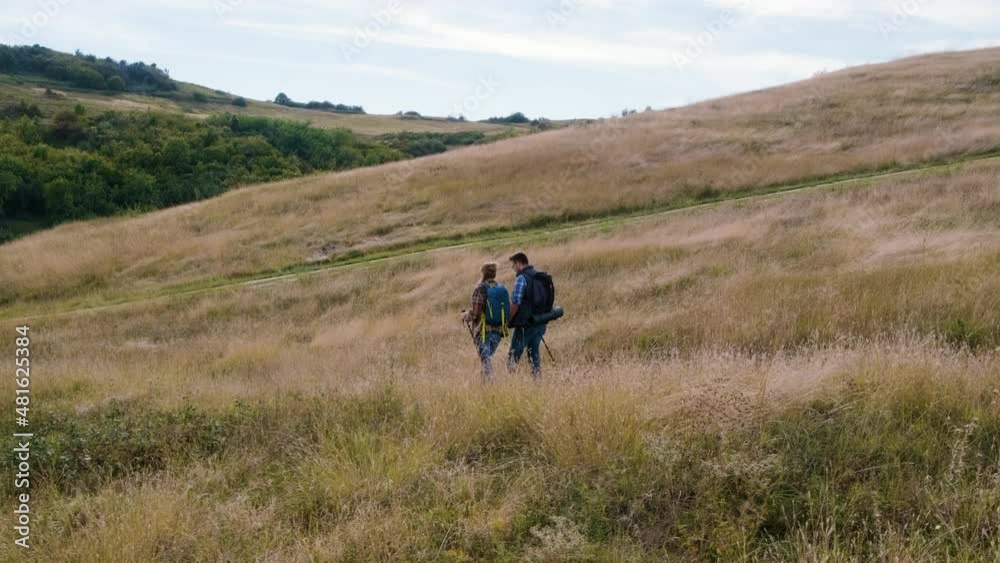 Couple with backpacks hiking together on countryside. Couple with backpacks hiking together on countryside.