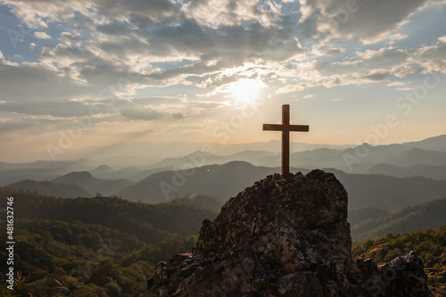 Silhouettes of crucifix symbol on top mountain with bright sunbeam on the colorful sky background