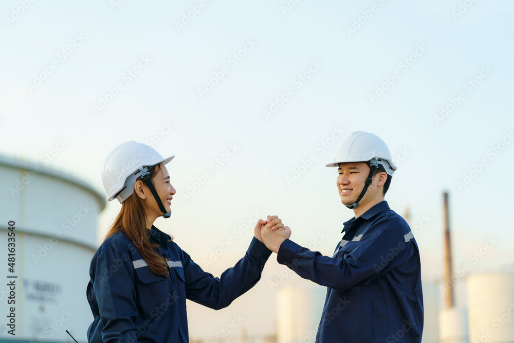 Asian engineer technicians man and woman shake hands showing how glad they were completing their mission at the oil refinery. Asian engineer technicians man and woman shake hands showing how glad they were completing their mission at the oil refinery.