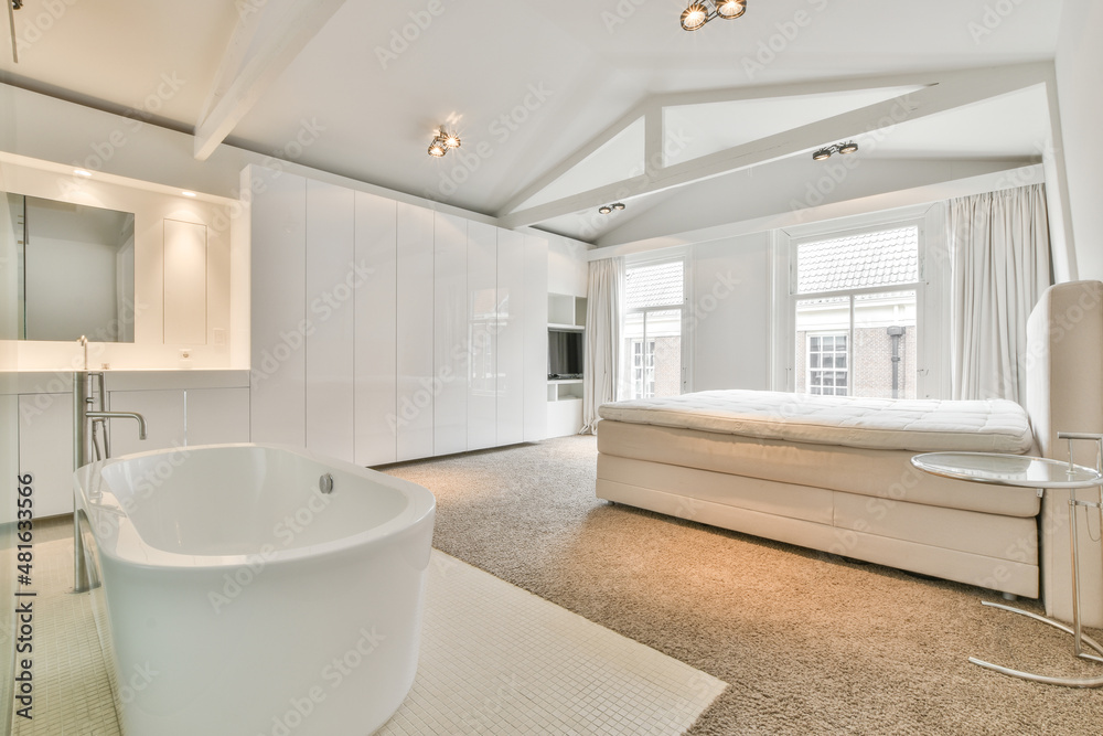 Bathroom with white bath and couch against window Bathroom with white bath and couch against window
