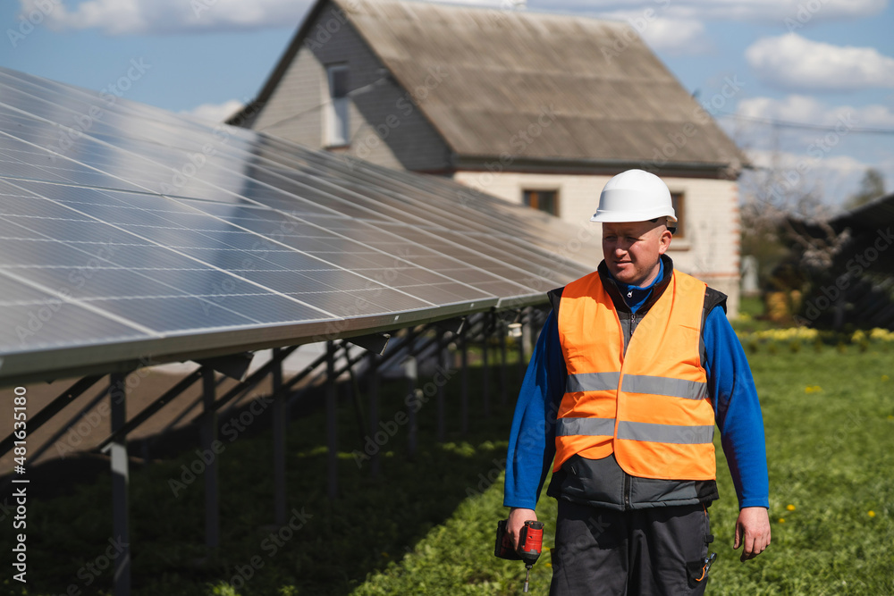 Male engineer with electric drill walks near the solar panels at power plant Male engineer with electric drill walks near the solar panels at power plant