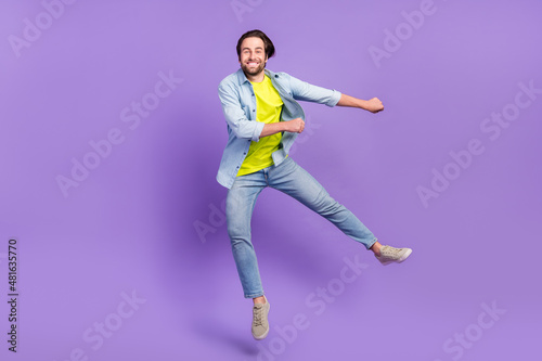Full size photo of funky smiling male jumping dancing in air fooling around isolated on violet color background