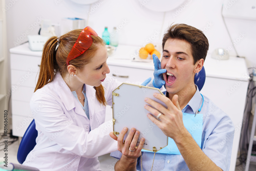 Fototapeta premium Female dentist showing teeth to patient
