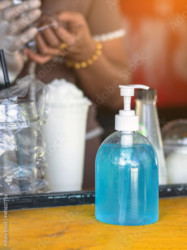 Blue alcohol gel bottle for hand cleaning to prevent the spreading of the Corona virus (Covid-19) for customer service in front of a coconut smoothie shop. New normal lifestyle. Health care concept.