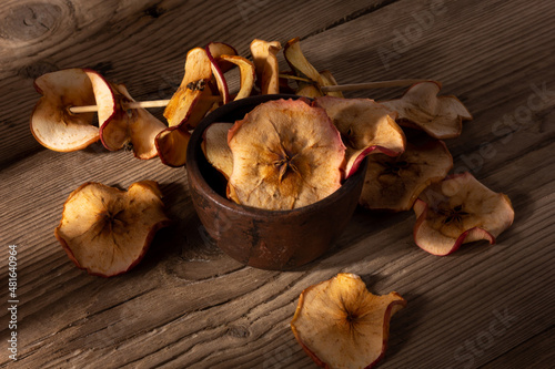 Dried apple chips in a bowl on wooden background