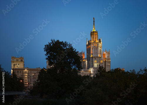 The High-rise building on the Kotelnicheskaya Embankment of Moskva river called Stalin skyscraper. With city lights. Evening blue sky.