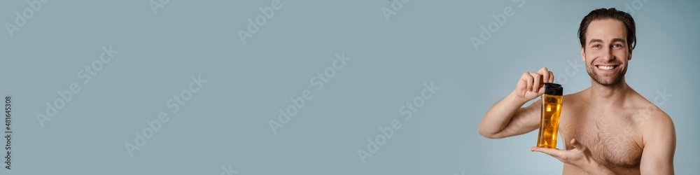 Close up of a smiling young nude man presenting shampoo