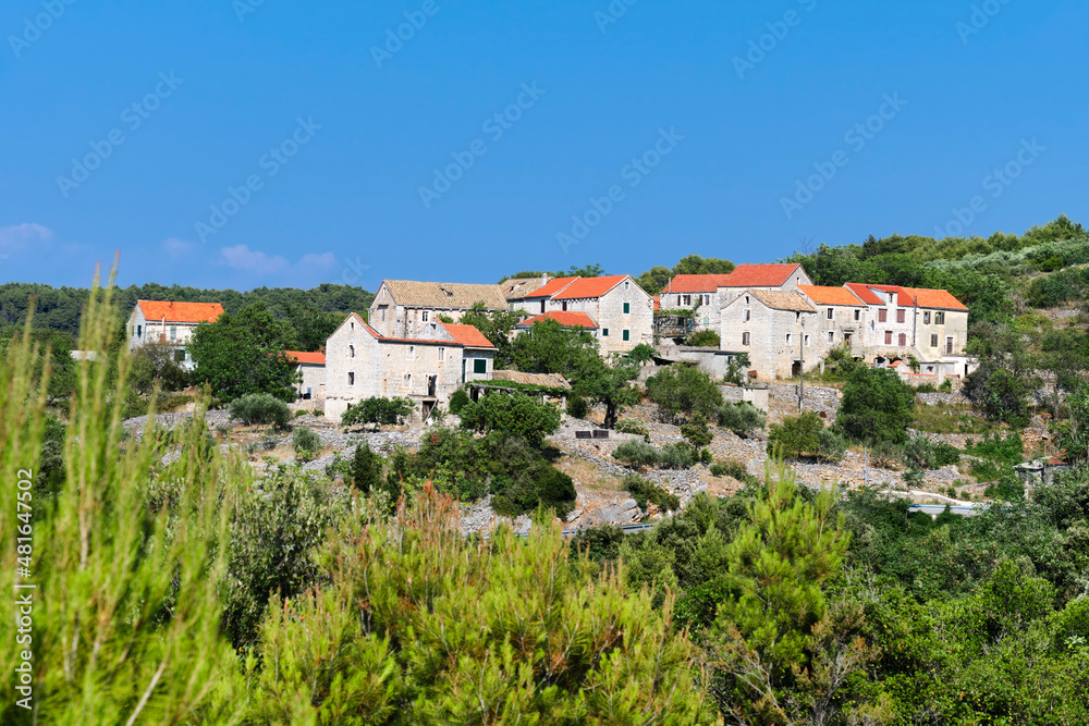 Old village in mountains of Hvar island in Croatia on old mountain road between coastal towns. Old stone cottage houses under red tile roofs.